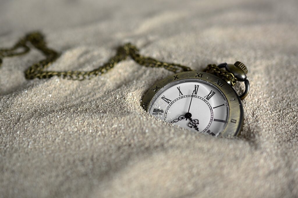 pocket watch partially buried in sand